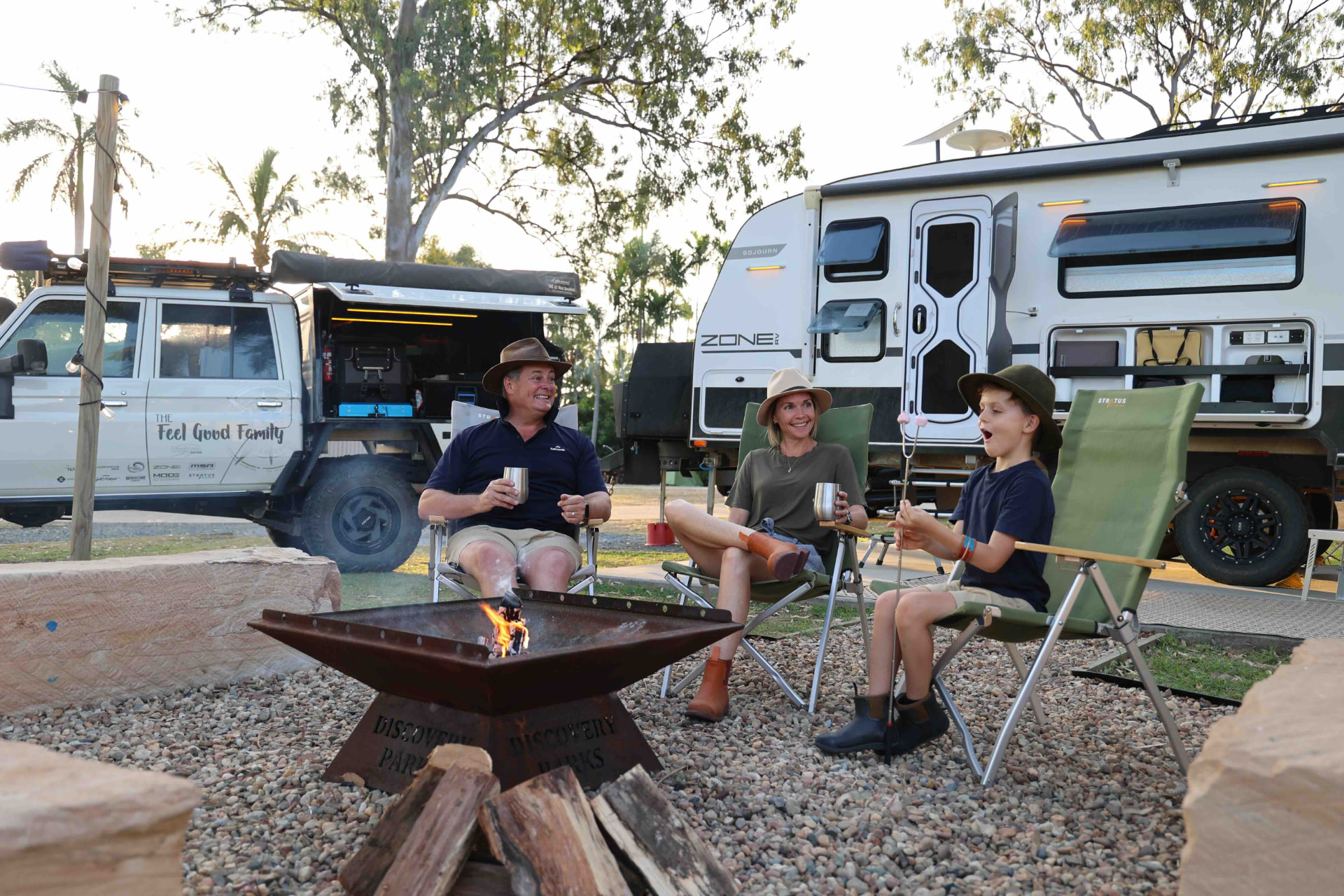 The Feel Good Family relaxing around the campfire beside their caravan