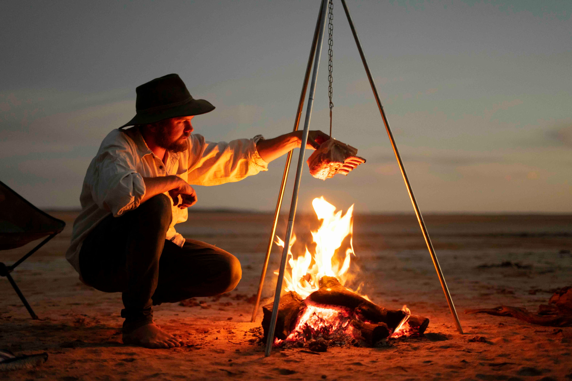 Harry Fisher cooking over a campfire at sunset