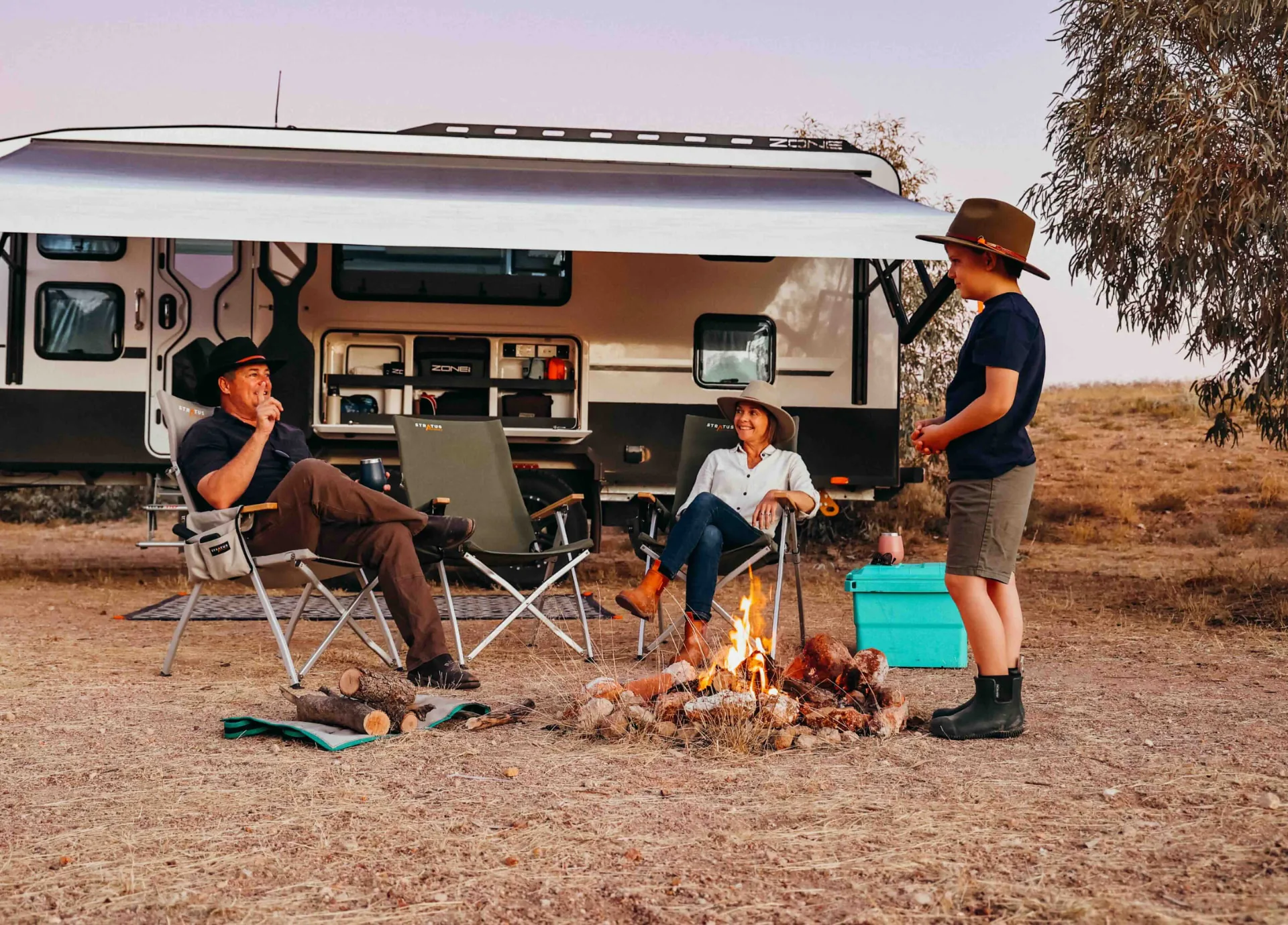 Katie, Paul and Jasper sharing time around a campfire beside their caravan
