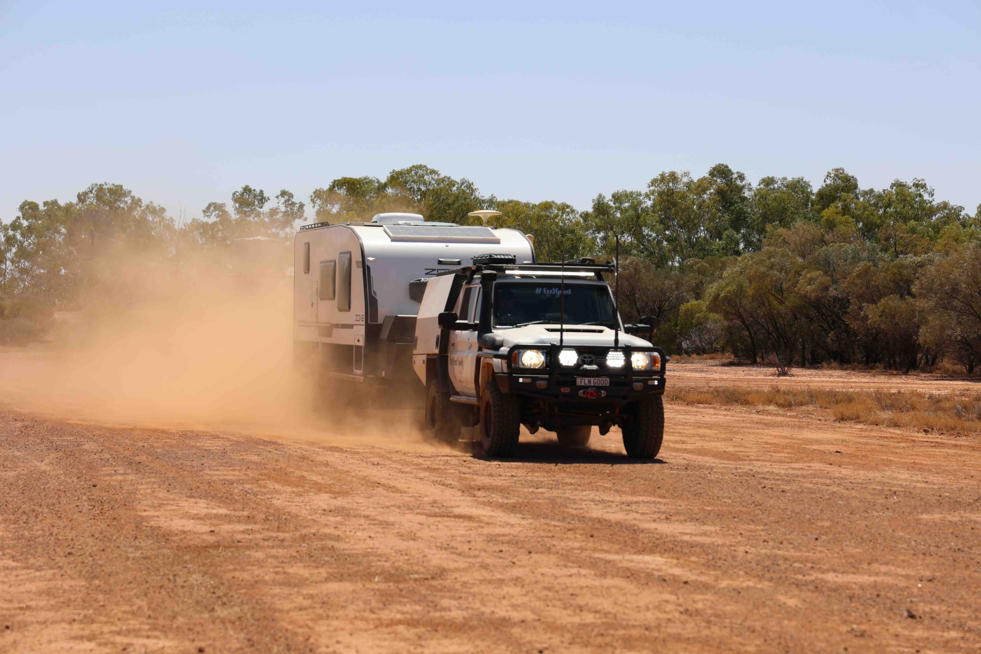The Feel Good Family towing their caravan along a dusty outback road