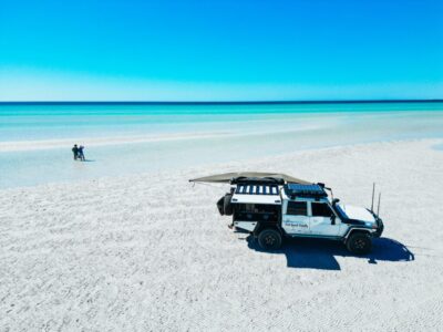 default Beautiful blue water beach with 4x4 vehicle and family enjoying the water